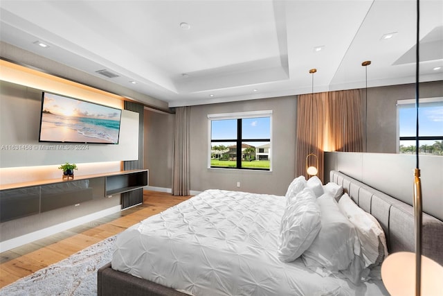 bedroom featuring light wood-type flooring and a tray ceiling