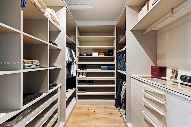 walk in closet with light hardwood / wood-style floors