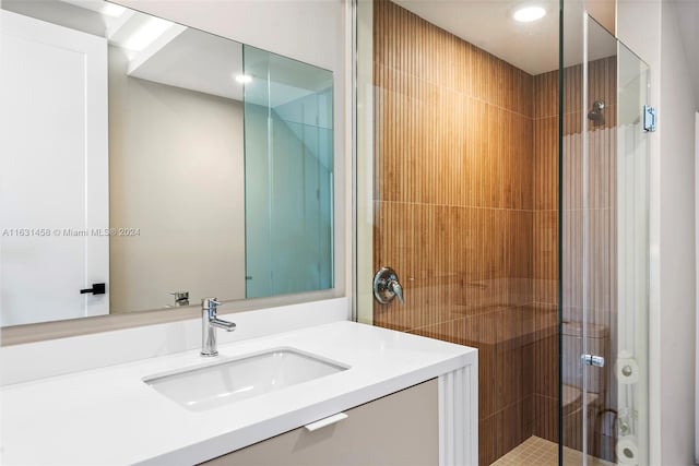 bathroom featuring a shower with shower door and vanity