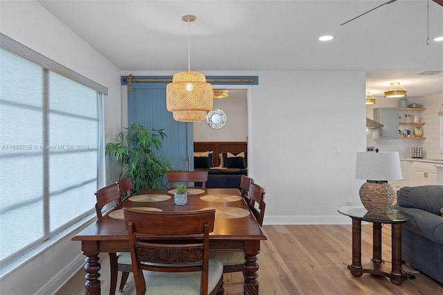 dining space featuring a barn door, plenty of natural light, and light wood-type flooring