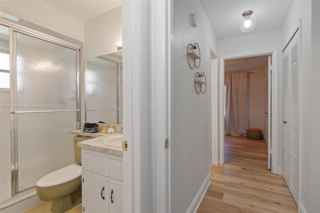 bathroom featuring vanity, toilet, wood-type flooring, and walk in shower