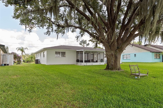 rear view of house featuring a sunroom, a yard, and central AC