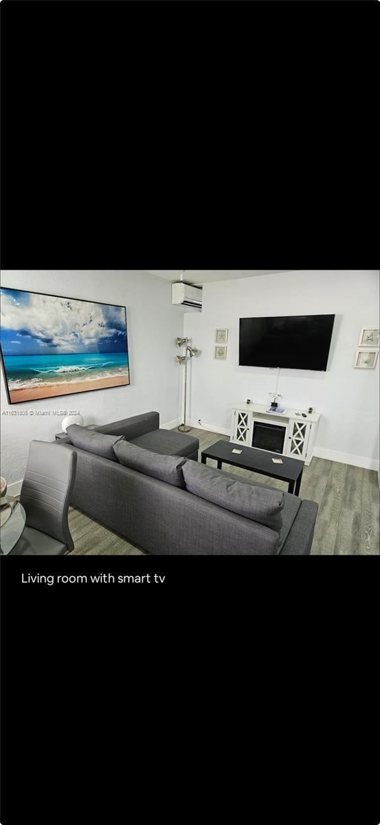 living area with wood finished floors and a wall mounted AC