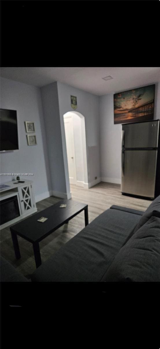 living area featuring arched walkways, light wood finished floors, and baseboards