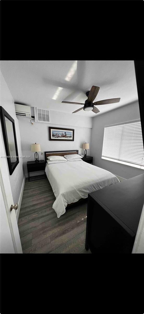 bedroom with ceiling fan, an AC wall unit, dark wood-type flooring, and visible vents