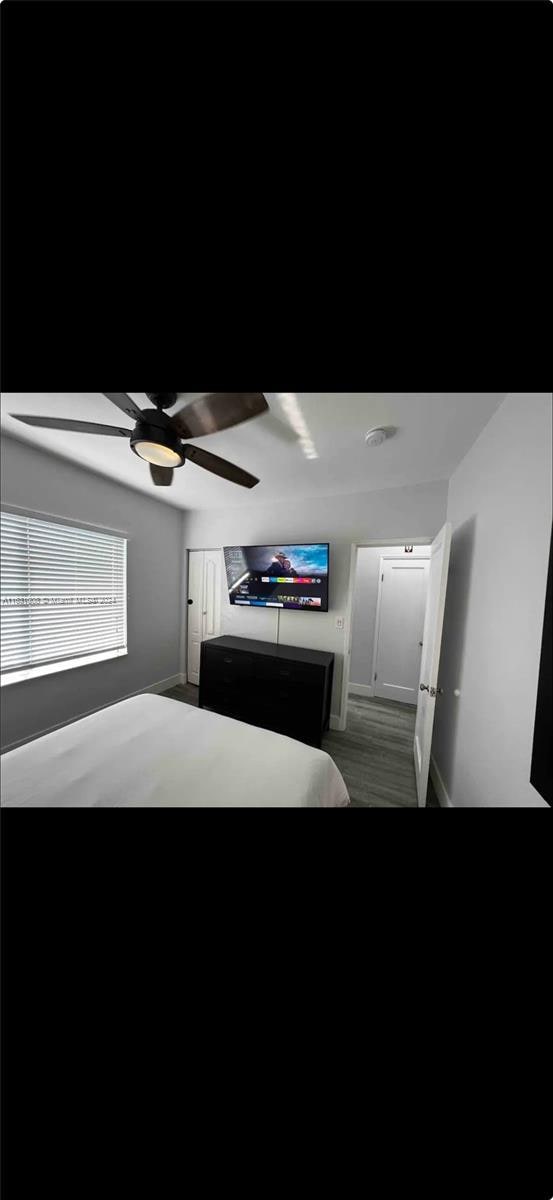 bedroom featuring dark wood-type flooring, a ceiling fan, and baseboards