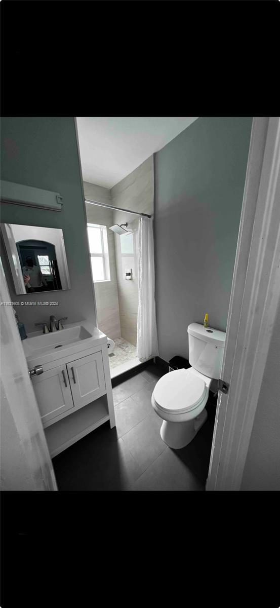 full bathroom with toilet, a stall shower, tile patterned floors, and vanity