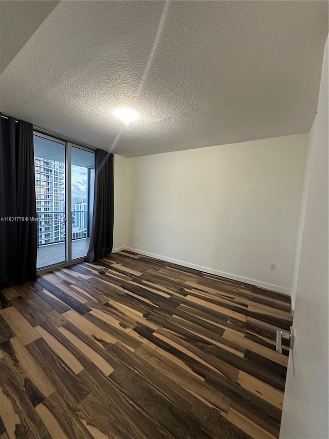 empty room featuring a wall of windows, a textured ceiling, and dark hardwood / wood-style floors