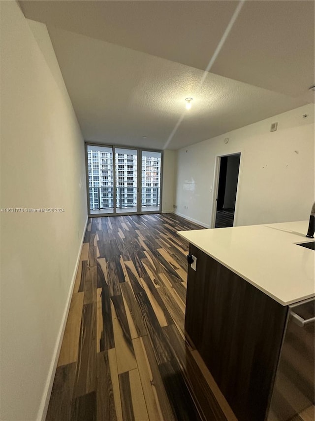 interior space featuring dark brown cabinetry, dark wood-type flooring, a textured ceiling, and floor to ceiling windows