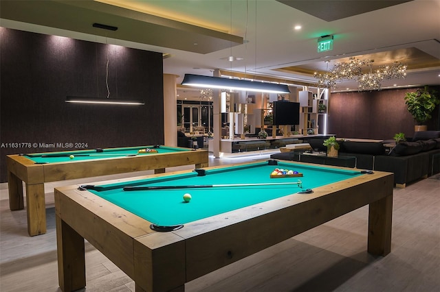 game room featuring pool table, light wood-type flooring, and a raised ceiling