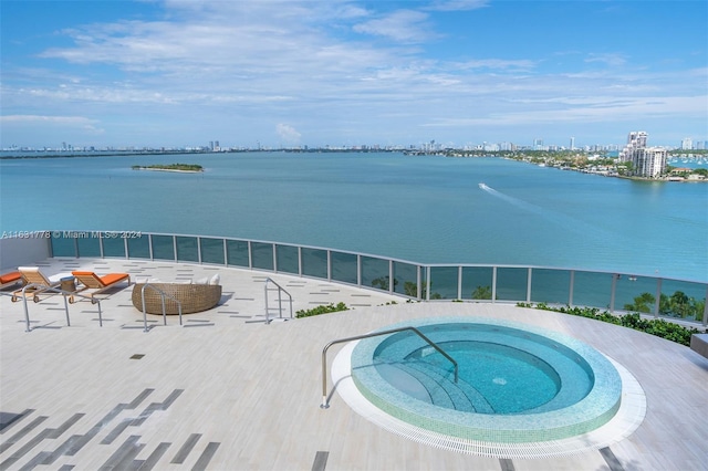 view of pool featuring an in ground hot tub, a water view, and a patio area