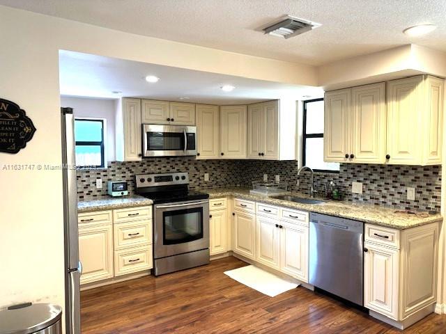 kitchen with sink, decorative backsplash, stainless steel appliances, and dark hardwood / wood-style flooring