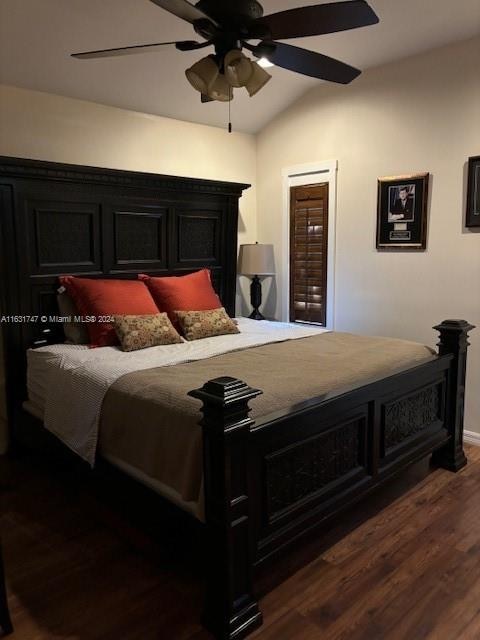 bedroom with dark hardwood / wood-style flooring, vaulted ceiling, and ceiling fan