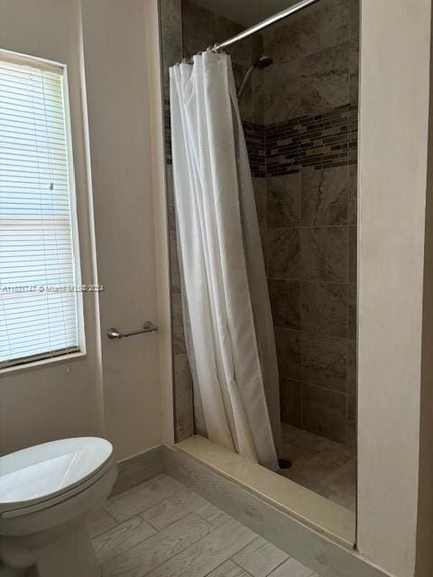 bathroom with toilet and a shower with curtain