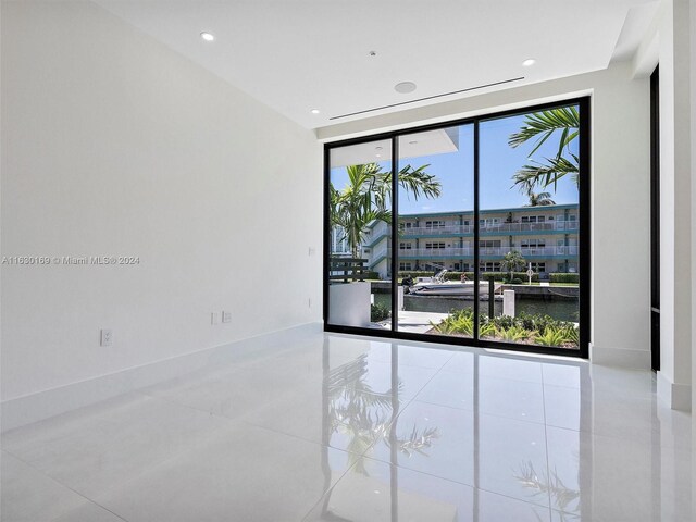 tiled spare room with a water view and a wall of windows