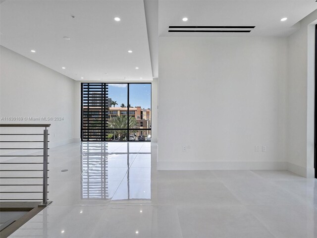 tiled spare room featuring a wall of windows