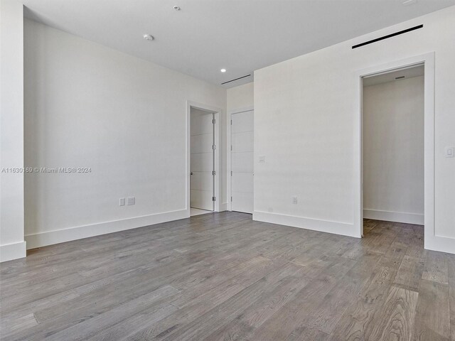 unfurnished bedroom with a walk in closet and light hardwood / wood-style floors