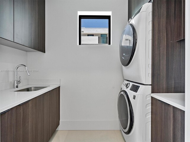 laundry room featuring sink, cabinets, and stacked washer / dryer