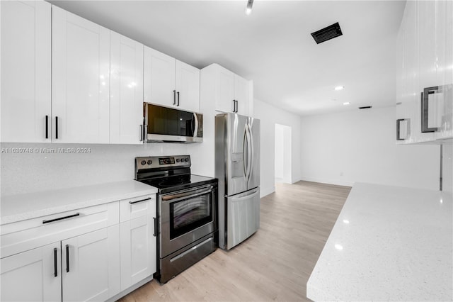 kitchen with white cabinetry, stainless steel appliances, and light hardwood / wood-style flooring