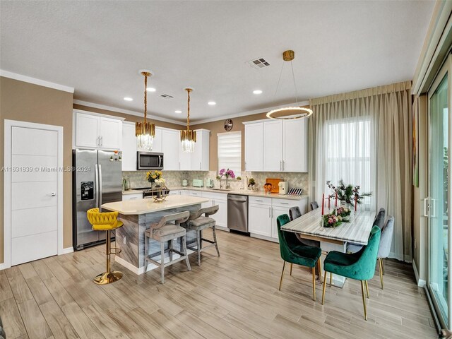 kitchen featuring tasteful backsplash, hanging light fixtures, appliances with stainless steel finishes, and a kitchen island