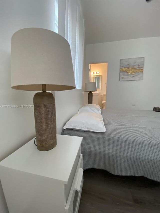 bedroom with ensuite bathroom and dark hardwood / wood-style floors