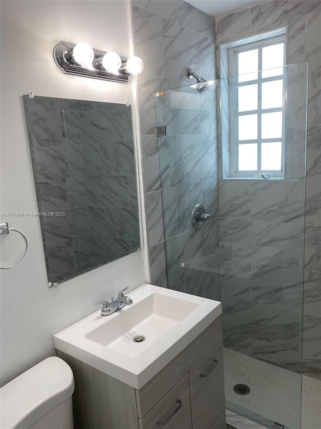 bathroom featuring vanity, a tile shower, and toilet