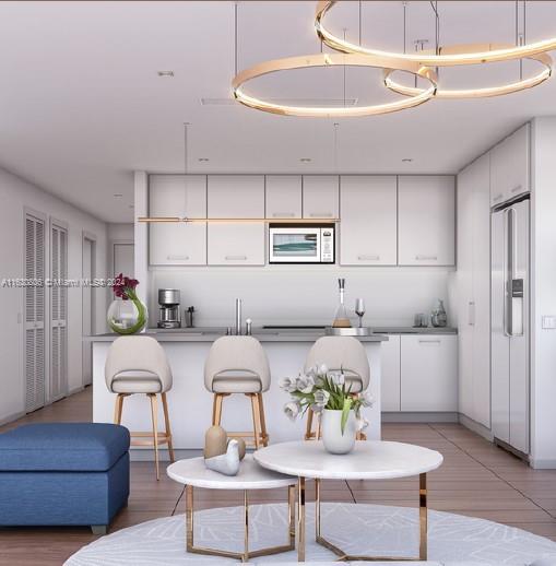 kitchen with white cabinets, built in microwave, decorative light fixtures, and white refrigerator with ice dispenser