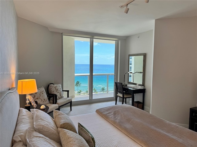 bedroom featuring expansive windows, a water view, and track lighting