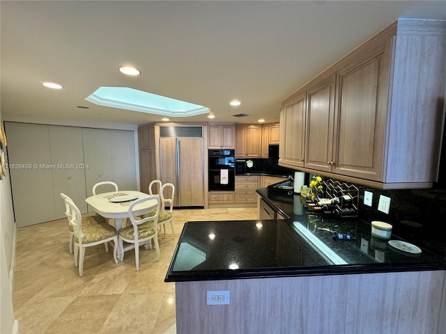 kitchen featuring light brown cabinets, a skylight, tasteful backsplash, paneled built in fridge, and black double oven