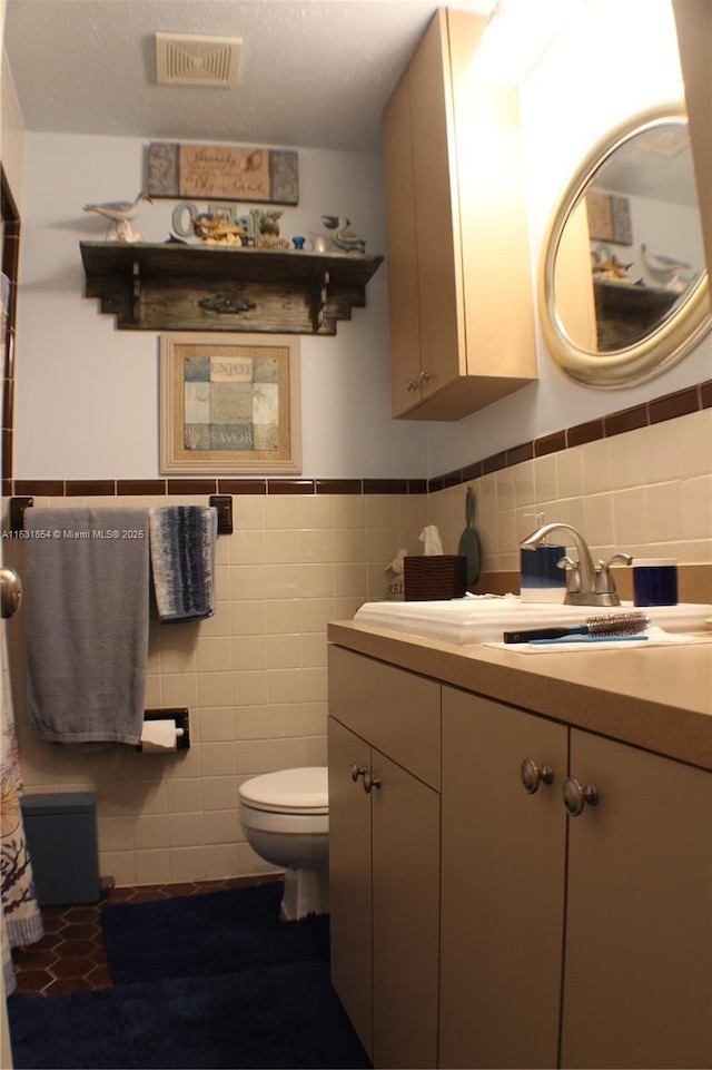 bathroom with vanity, tile walls, and toilet