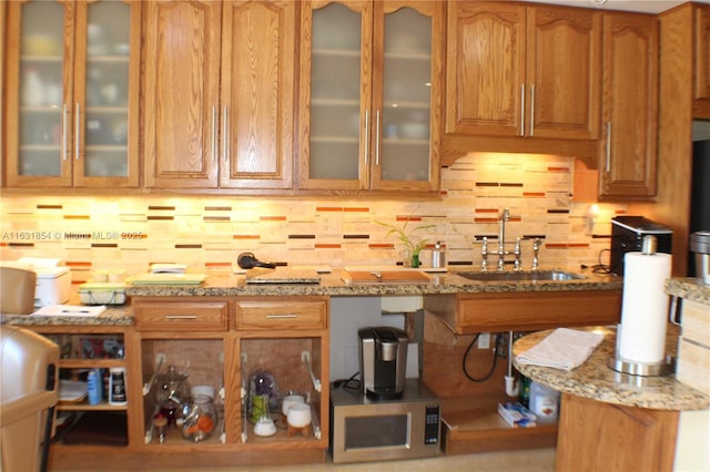 kitchen featuring decorative backsplash, sink, and light stone counters