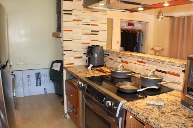 kitchen with decorative backsplash, light stone counters, and stainless steel electric range oven