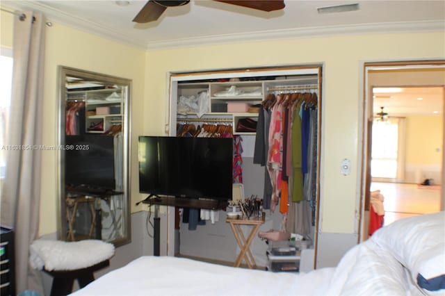 bedroom with crown molding, ceiling fan, and two closets