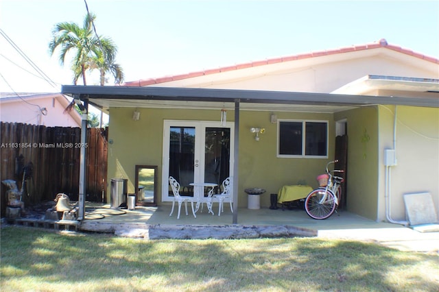 back of property featuring french doors, a patio area, and a lawn