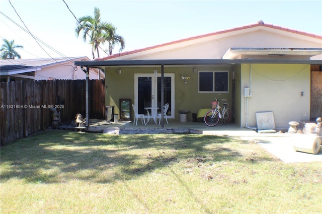 rear view of house with french doors, a patio area, and a lawn