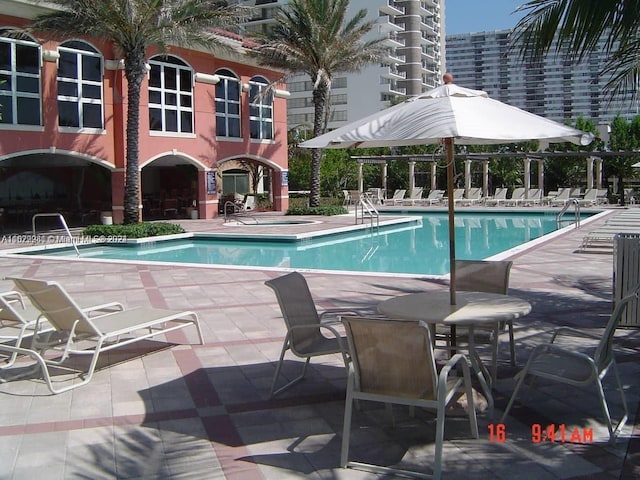 view of pool with a hot tub and a patio