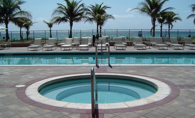 view of swimming pool featuring a patio and a hot tub