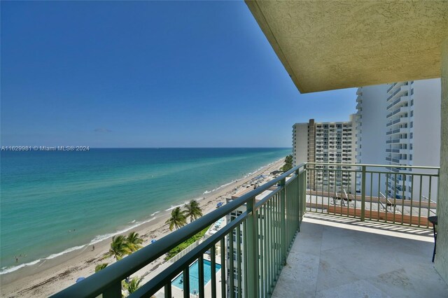 balcony featuring a beach view, a water view, and a community pool