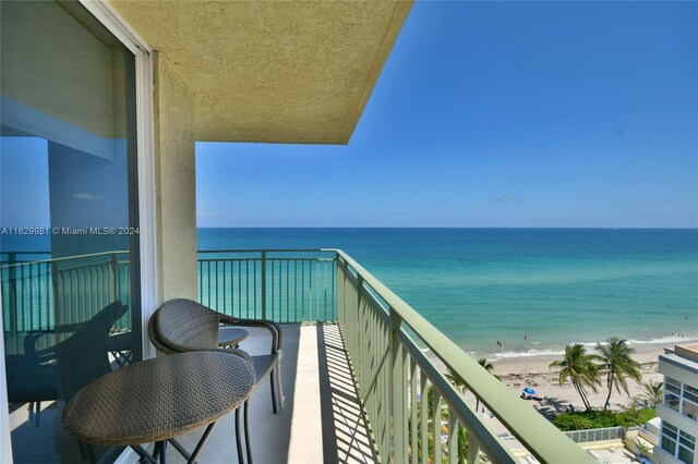 balcony with a water view and a view of the beach