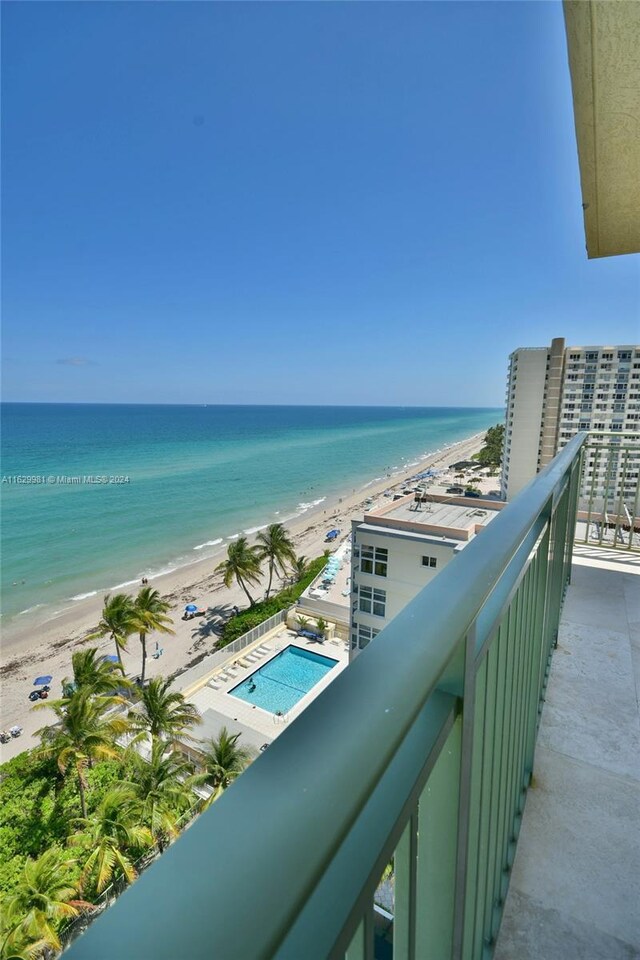 balcony with a water view, a beach view, and a community pool