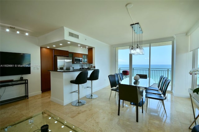 dining area featuring expansive windows, a water view, and an inviting chandelier