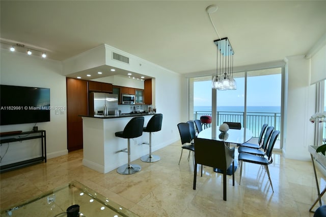 tiled dining area featuring a water view, rail lighting, and expansive windows