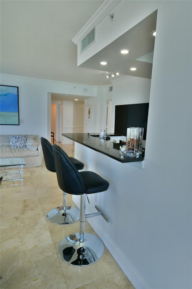 kitchen featuring kitchen peninsula, a breakfast bar, and light tile patterned floors