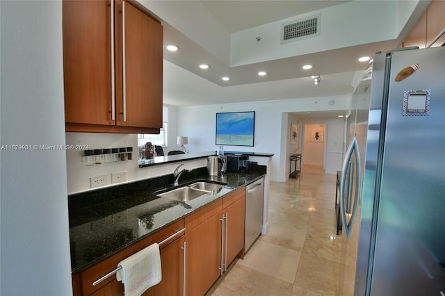 kitchen featuring appliances with stainless steel finishes, sink, and dark stone countertops