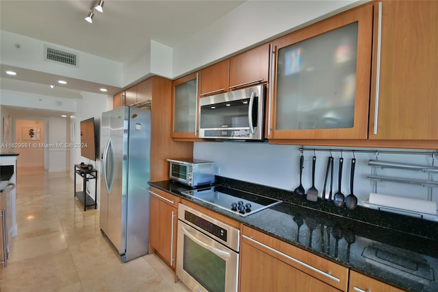 kitchen with rail lighting, dark stone countertops, appliances with stainless steel finishes, and light tile patterned floors