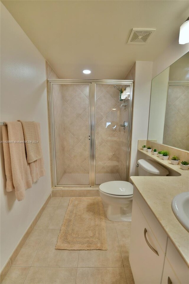 bathroom featuring a shower with shower door, vanity, tile patterned floors, and toilet