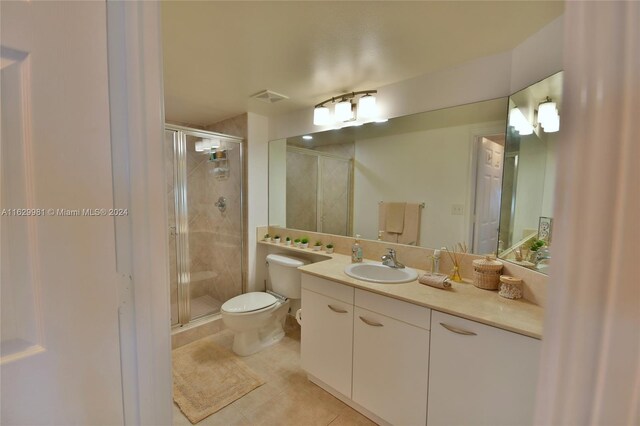 bathroom with vanity, tile patterned floors, a shower with door, and toilet