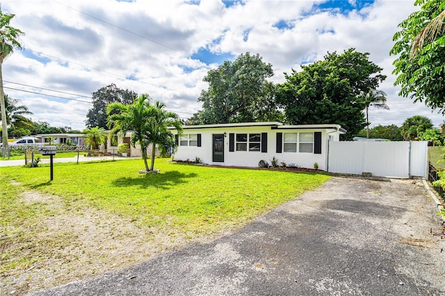 view of front facade with a gate, driveway, a front lawn, and fence