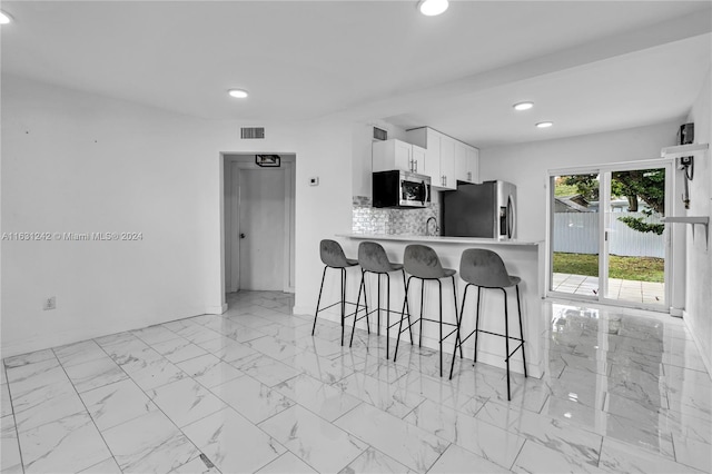 kitchen featuring a kitchen breakfast bar, marble finish floor, visible vents, and appliances with stainless steel finishes