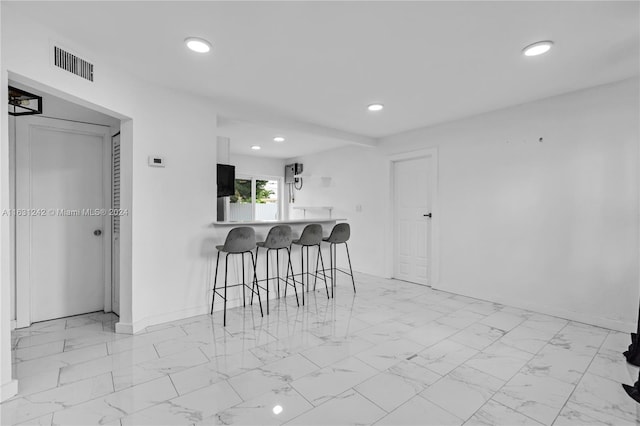 kitchen with visible vents, marble finish floor, a breakfast bar, recessed lighting, and baseboards